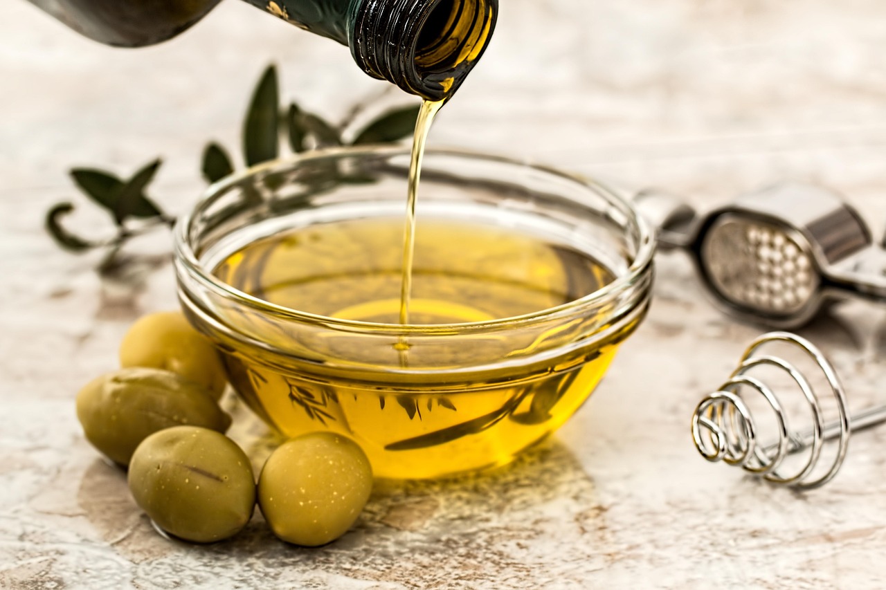 Bottiglia di olio d'oliva su tavolo con ingredienti freschi per ridurre la glicemia.